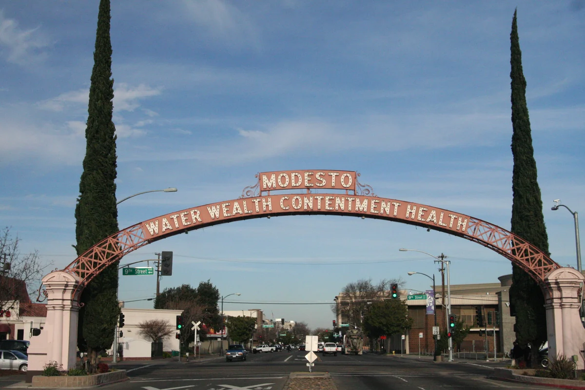 The Modesto Arch and its Water, Wealth, Contentment, Health motto framed by cypress trees Destination photo. Not the club or its route.